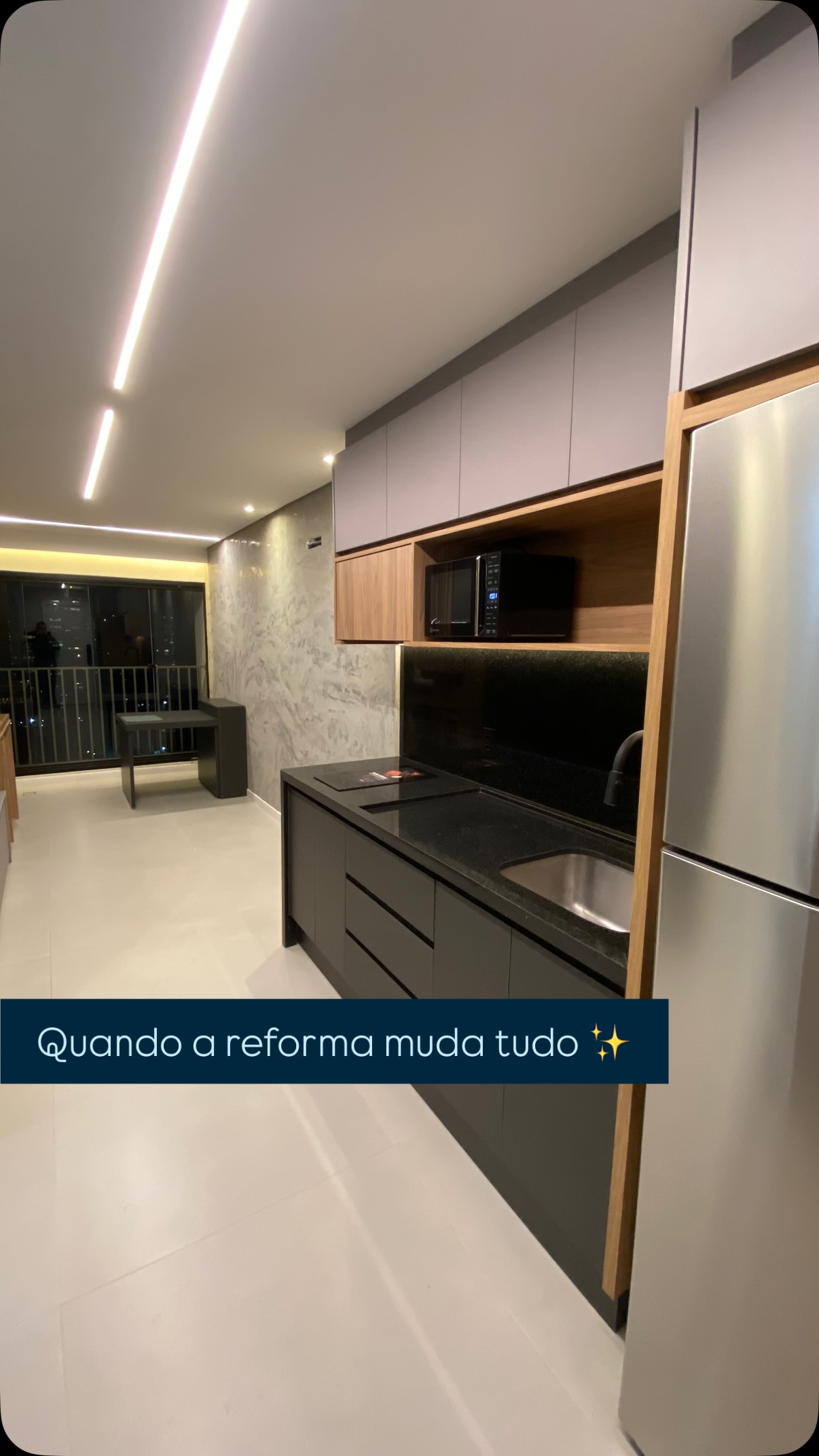 Cozinha reformada com marcenaria escura e iluminação linear